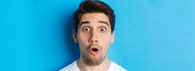 Headshot of surprised man gasping wondered saying wow and looking amazed at camera standing over blu