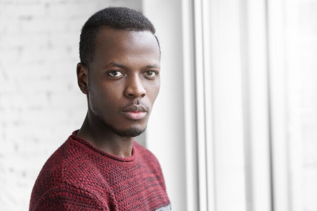 Headshot of young Afro-American man wearing warm jersey sweater staring at camera