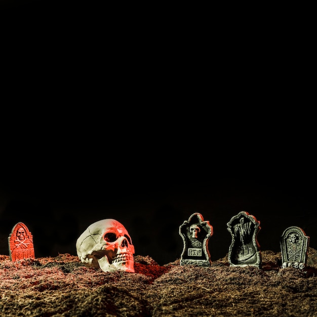 Бесплатное фото Надгробные плиты и череп на почве