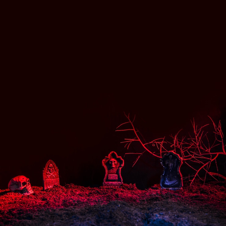 Free Photo headstones and skull illuminated by red light on ground