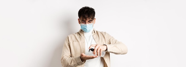 無料写真 健康コビッドと検疫のコンセプトメガネとフェイスマスクを着た若いヒスパニック系の男が手指消毒剤を使用