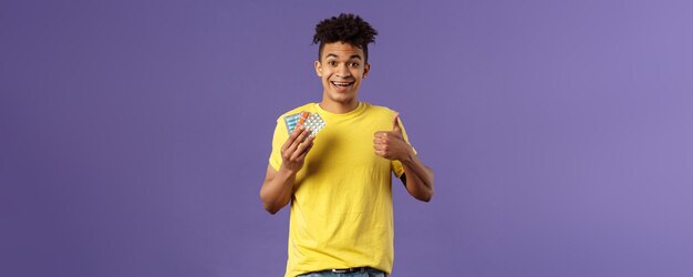 Health influenza covid concept portrait of young healthy man got better show thumbsup holding drugs