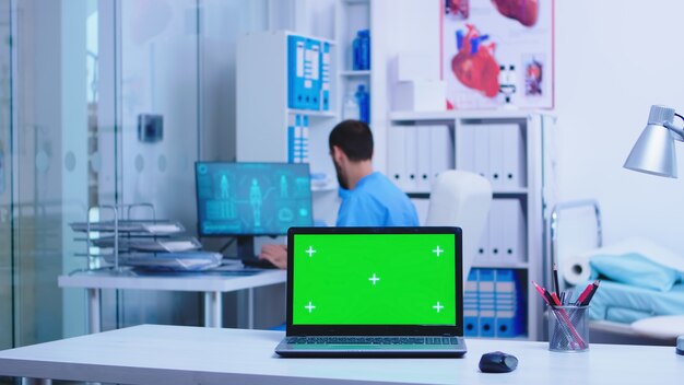 Health physician leaving clinic cabinet and laptop with copy space available while nurse typing notes on computer. Notebook with replaceable screen in medic clinic.