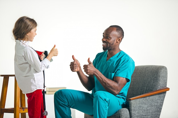 Healthcare and medical concept - doctor and girl with stethoscope in hospital