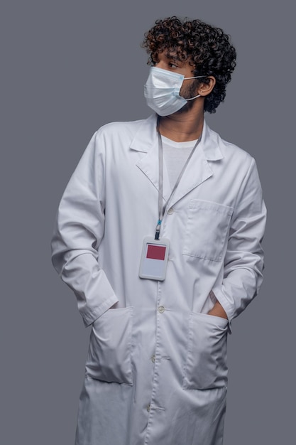 Бесплатное фото Медицинский работник, одетый в лабораторный халат, смотрит в сторону