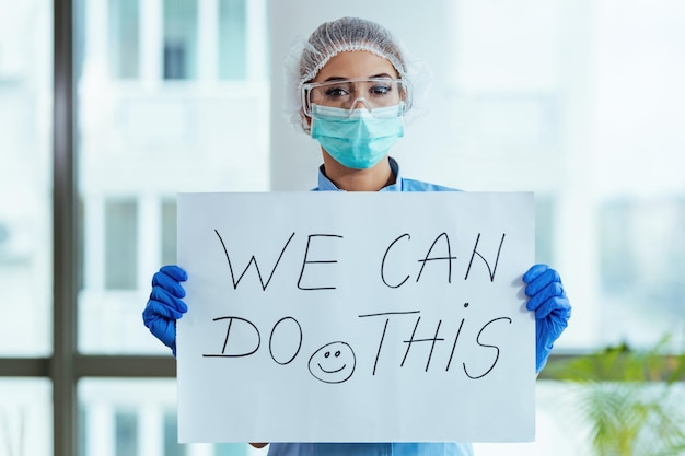 Free photo healthcare worker holding placard with supportive 'we can do this' message while standing in the hospital