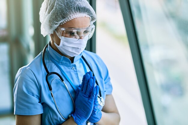 Healthcare worker praying with hands clasped while working at the hospital