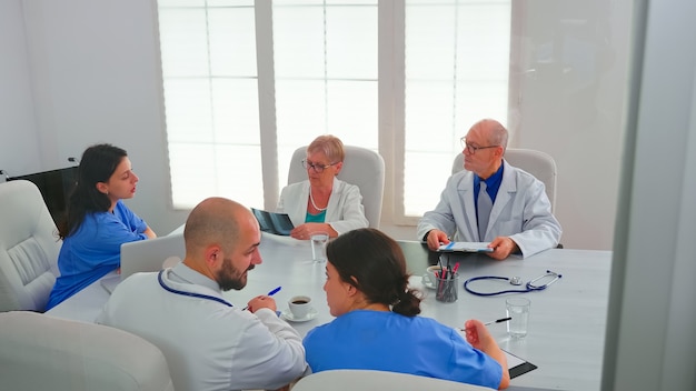 Free photo healthcare workers having meeting in hospital conference room about symptoms of patients analysing x-ray. clinic expert therapist talking with colleagues about disease, medicine professional