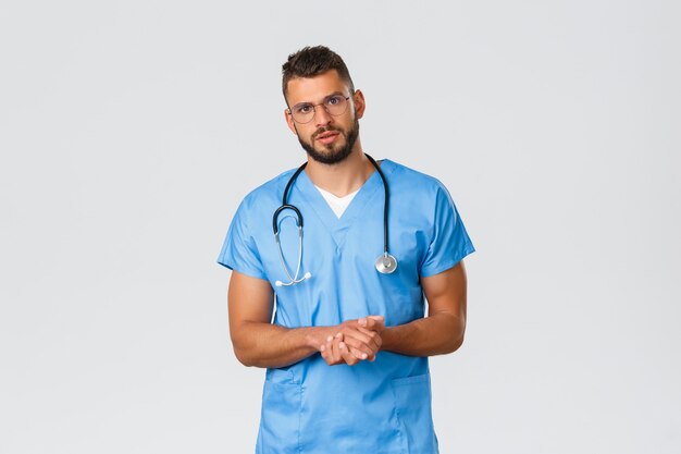 Healthcare workers, medicine, covid-19 and pandemic self-quarantine concept. Professional doctor, surgeon or physician in clinic talking to patient with serious worried face, wear blue scrubs
