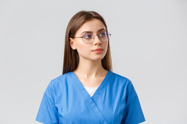 Медицинские работники, медицина, страхование и концепция пандемии covid-19. Задумчивая довольно профессиональная медсестра, врач в очках и скрабах, любопытно выглядящая, думающая, наблюдающая что-то