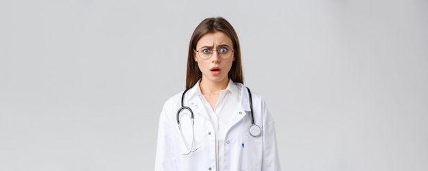 Healthcare workers medicine insurance and covid19 pandemic concept Shocked nervous female doctor in white scrubs and glasses doctor gasping and staring concerned camera