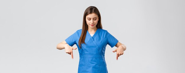의료 종사자들은 바이러스 covid19 테스트 선별 의학 개념을 예방합니다. 예쁜 여성 간호사 또는 파란색 수술복을 입은 의사 의사 유니폼을 가리키고 호기심 많은 독서 배너를 내려다보고 있습니다