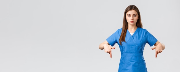 Gli operatori sanitari prevengono il concetto di medicina per lo screening dei test del virus covid19 un medico professionista serio o un infermiere in camice blu che punta il dito verso il basso fornisce informazioni sul coronavirus