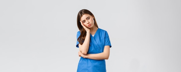 Healthcare workers prevent virus insurance and medicine concept Exhausted and sleepy female nurse doctor in scrubs lean on palm look tired feel fatigue from night shift at hospital