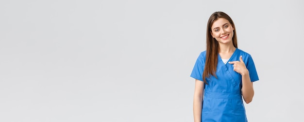 의료 종사자들은 바이러스 보험 및 의학 개념을 예방합니다. 파란색 수술복을 입은 아름다운 간호사 여의사가 환자를 구할 준비가 되어 있음을 가리키고 있습니다.