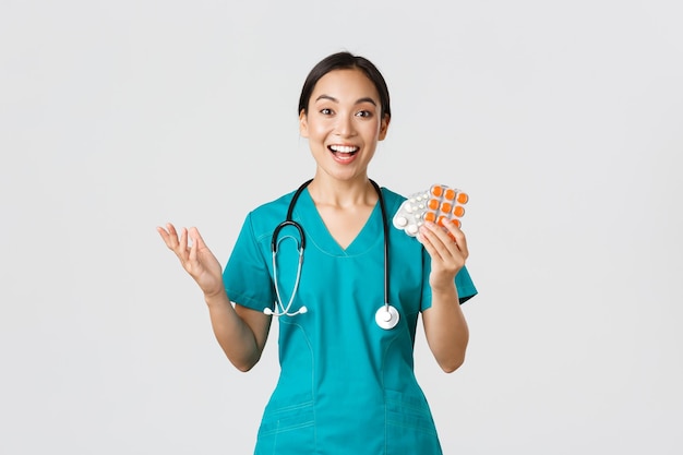 Healthcare workers preventing virus quarantine campaign concept Excited happy asian female physician nurse in medical mask showing amazing new medication recommend drugstore