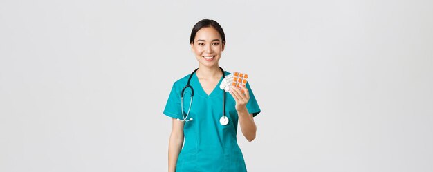 Healthcare workers, preventing virus, quarantine campaign concept. Friendly-looking female asian nurse, doctor explain patient medication prescription, showing drugs and smiling, white background.