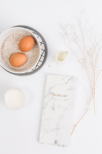 Healthy baking ingredient with notepad against white surface