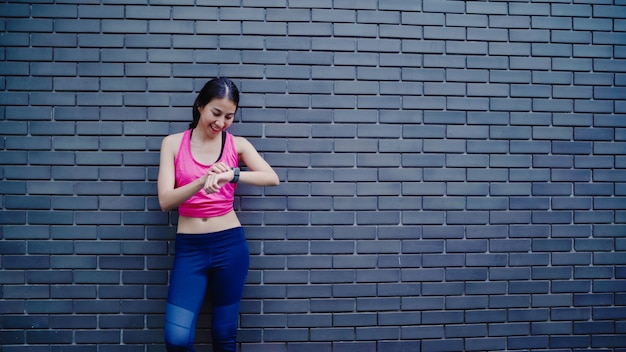 Free photo healthy beautiful young asian athlete woman setting and checking progress looking heart rate monitor