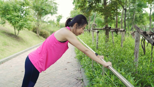 Belle giovani donne asiatiche dell'atleta in abbigliamento sportivo gambe riscaldamento e stretching lei braccia