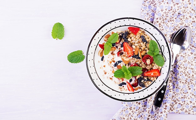 Healthy breakfast - granola, strawberries, cherry, honeysuckle berry, nuts and yogurt in a bowl. vegetarian concept food. top view