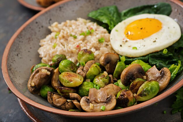 Healthy breakfast. Oat porridge, egg and salad of baked vegetables - mushrooms and Brussels sprouts..