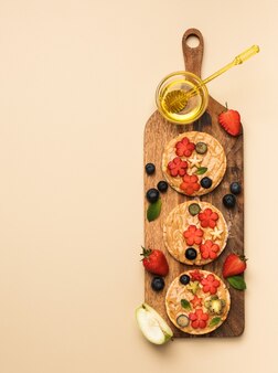 木​の​板​、​上面図​に​果物​と​蜂蜜​と​ベリー​と​ピーナッツ​バター​の​ヘルシーな​朝食​サンドイッチ​。​健康​食品​の​コンセプト
