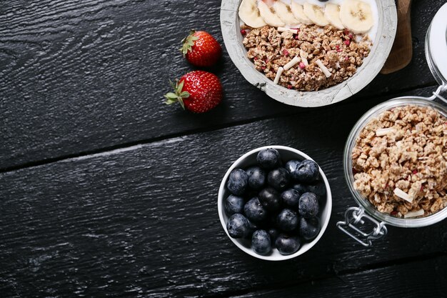 Здоровый завтрак с хлопьями и фруктами на черном деревянном столе