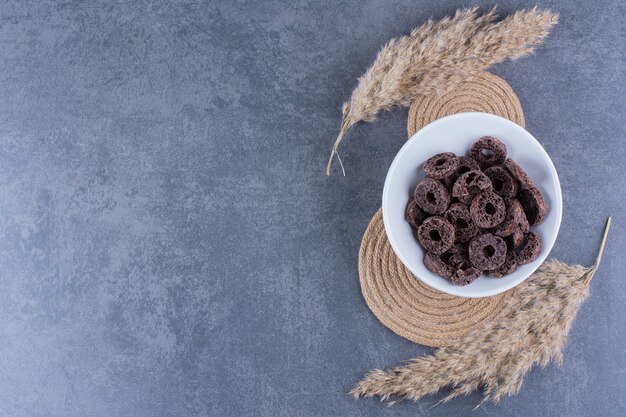 Healthy breakfast with chocolate corn rings in a plate on a stone surface