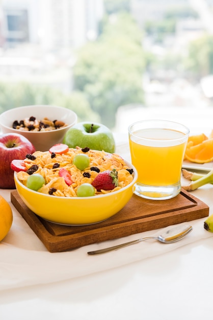 コーンフレークで健康的な朝食。ドライフルーツ;テーブルの上のリンゴとジュースのガラス