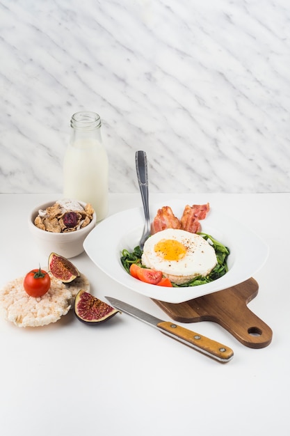 Healthy breakfast with milk bottle; cornflakes; fig and rice cracker against marble textured backdrop