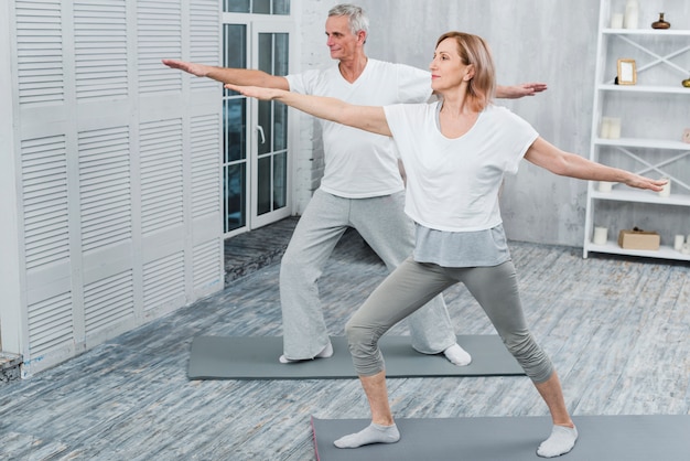 Healthy couple performing exercising on yoga mat at home