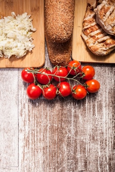 Healthy delicious grilled chicken on wooden board next to healthy bread, tomatoes and salad. healthy lifestyle and eating