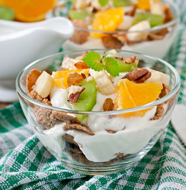 Dessert sano con muesli e frutta in una ciotola di vetro sul tavolo