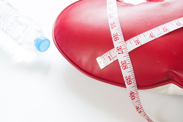 Healthy and diet concept with measuring tape wrapped around red heart on white background