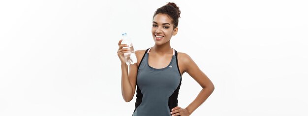 Healthy and Fitness concept beautiful African American girl in sport clothes holding plastic water bottle after workout Isolated on white studio background