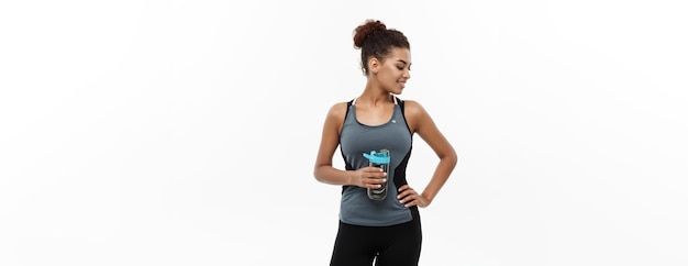 Free photo healthy and fitness concept beautiful african american girl in sport clothes holding water bottle after workout isolated on white studio background