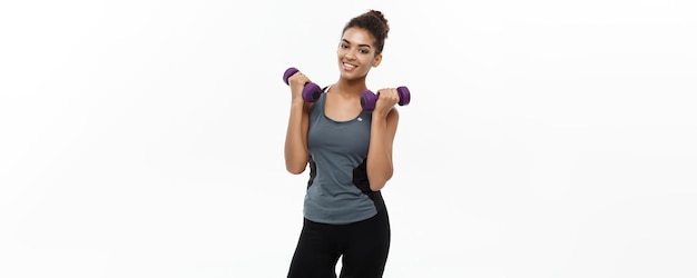 Healthy and Fitness concept Beautiful American African lady in fitness clothes workout with dumbbell Isolated on white background