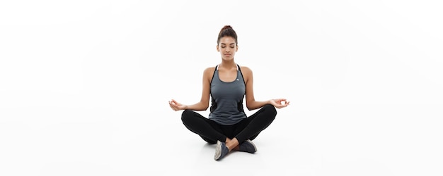 Healthy and Fitness concept Beautiful American African lady in fitness clothing doing yoga and meditation Isolated on white background