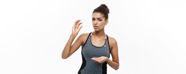 Free photo healthy and fitness concept closeup portrait of beautiful african american taking a pill of cod liver oil isolated on white studio background