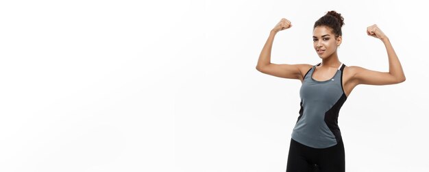 Healthy and fitness concept portrait of young beautiful african american showing her strong muscle