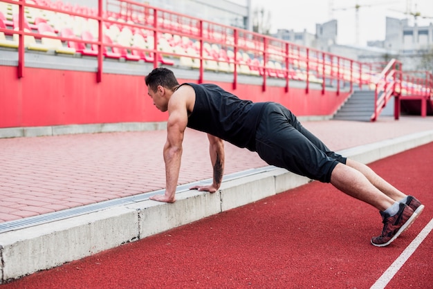 Healthy fitness young man on race track doing pushups