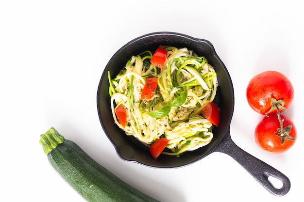 健康食品のコンセプト自家製ギルテンフリーズッキーニ麺 鉄のフライパンでトマトのパスタ プレミアム写真