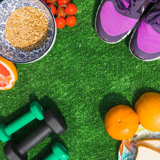 Healthy food with pair of sport shoes and dumbbells on turf