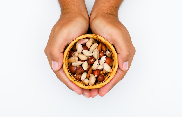 Healthy foods concept on white background flat lay. hands holding dish with mixed nuts.