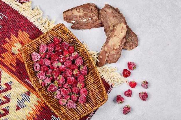 Healthy fresh raspberries in wooden basket with carved rug. 