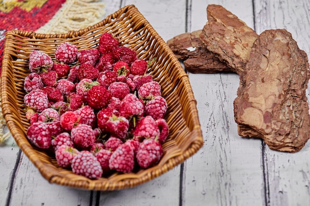 Free photo healthy fresh raspberries in wooden basket with carved rug.