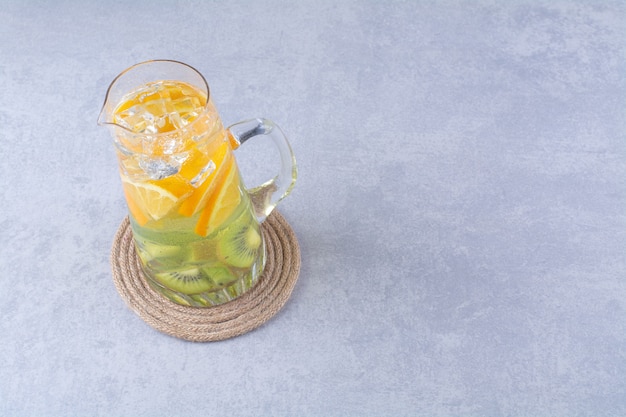 Healthy fruit juice in a carafe on marble table.