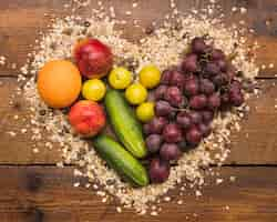 Free photo healthy fruits between heart shape made with oats and nut food on wooden desk