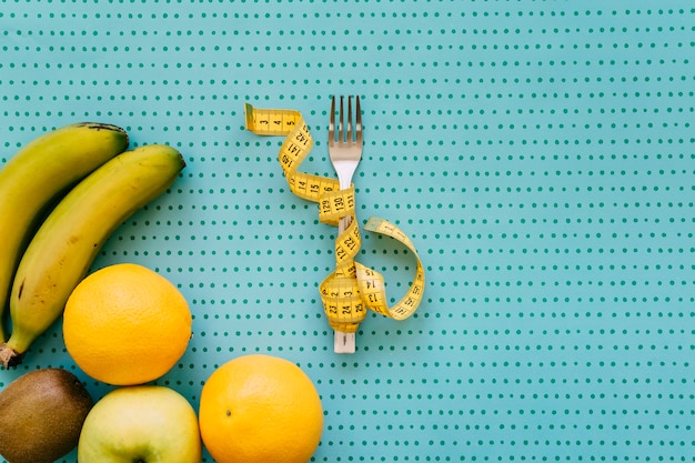 Healthy fruits and tape measure around fork